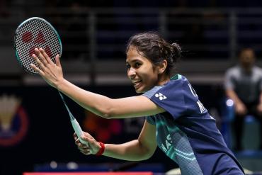 Летшанаа Карупатеван в тёмно-синей форме Yonex завершает удар с ракеткой в правой руке, на фоне размытая эмблема турнира. Фото: BWF/Badmintonphoto Летшанаа Карупатеван в тёмно-синей форме Yonex завершает удар с ракеткой в правой руке, на фоне размытая эмблема турнира. Фото: BWF/Badmintonphoto