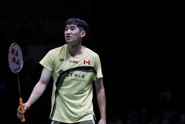 Виктор Лай в жёлтой майке с флагом Канады и надписью Mandarin Badminton держит ракетку с оранжевой рукояткой на тёмном фоне, кадр чемпионата мира (фото: BWF/Badmintonphoto — Jnanesh Salian) Виктор Лай в жёлтой майке с флагом Канады и надписью Mandarin Badminton держит ракетку с оранжевой рукояткой на тёмном фоне, кадр чемпионата мира (фото: BWF/Badmintonphoto — Jnanesh Salian)