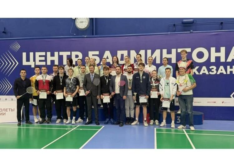 Общая фотография призёров всероссийских соревнований памяти Ф.Г. Валеева с медалями, грамотами и кубками на фоне синей стены «Центр бадминтона. Казань». Фото: НФБР (nfbr.ru).