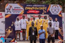 Призёрки женского парного разряда с медалями на подиуме под баннером Africa AirBadminton Championships Uganda 2026, перед ними стоят официальные лица. Фото: BWF/Badminton Confederation of Africa.