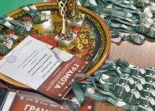 Хохломской поднос с наградным кубком, стопка грамот и связки зелёных лент с медалями «Памяти Ф.Г. Валеева» на столе перед награждением. Фото: НФБР (nfbr.ru).